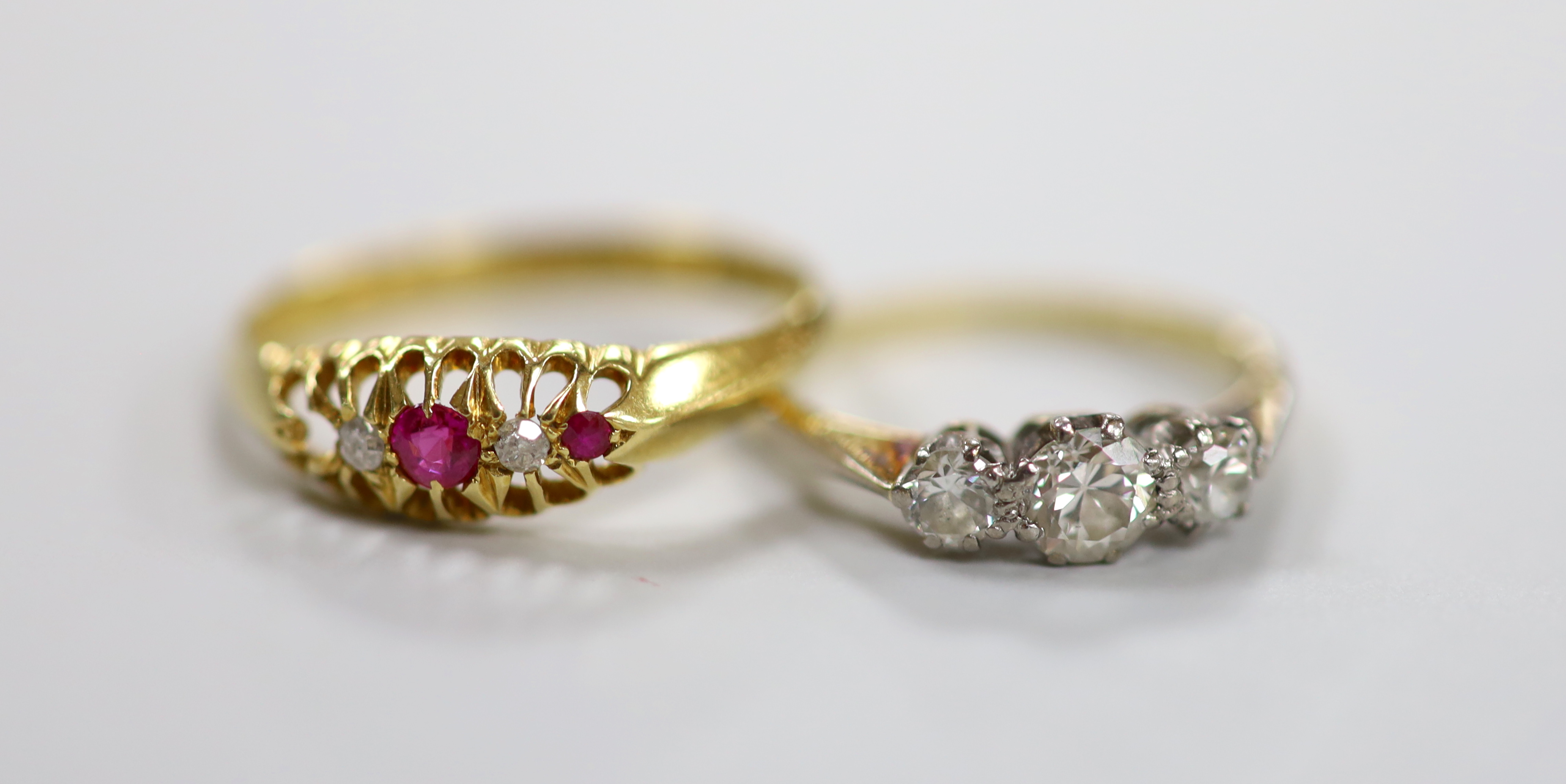 An 18ct, plat and three stone diamond set ring, size I and a George V 18ct gold and five stone ruby and diamond chip set ring, size P, gross weight 4.4 grams.